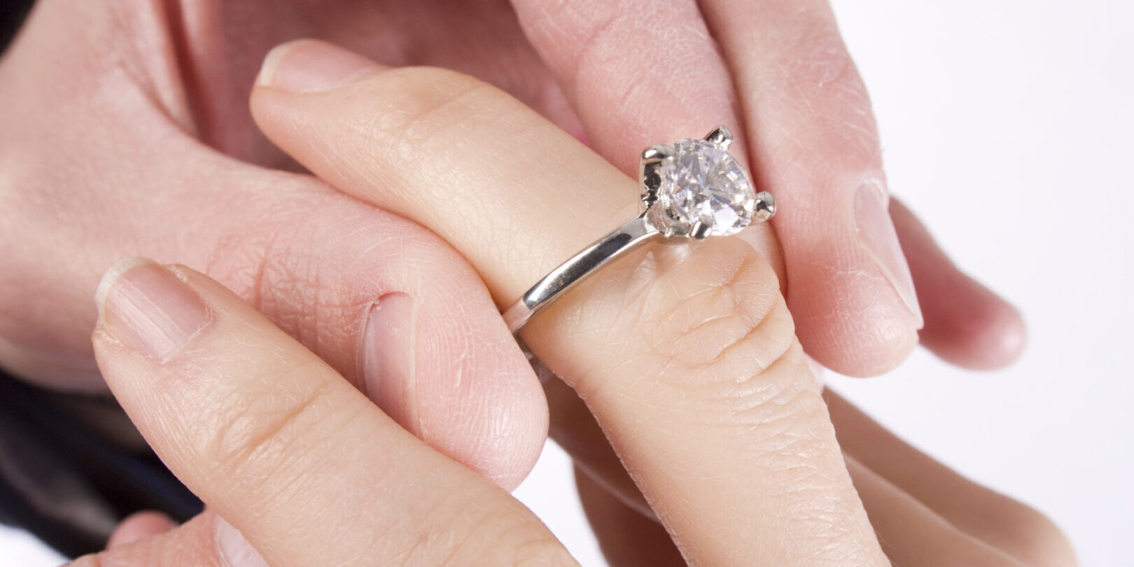 A man slides a diamond ring on his fiance's finger